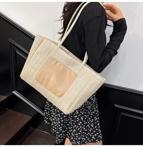 Detailed weave pattern and faux leather patch on a large straw tote bag with rope handles