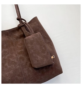 Detail of vintage brown leather tote bag showing textured grain and matching coin purse charm