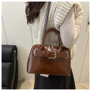 Macro detail of caramel brown leather shoulder bag featuring polished metal buckle design