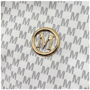 Macro shot of white pebble leather tote with grey M-pattern and gold logo emblem