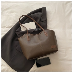 Macro detail of dark brown litchi pattern leather tote bag with branded tag