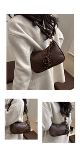 Detail of dark brown retro shoulder bag with knot strap and pretzel pendant