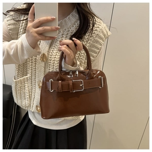 Detail of the glossy dark brown leather surface and silver metal buckle on the Boston bag