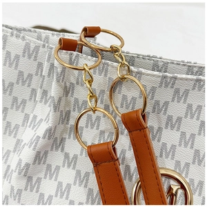 Detail of lychee pattern faux leather tote bag with gold M-logo pendant and chain hardware