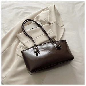 Detail of a deep brown faux leather shoulder bag with gold beads and knotted straps