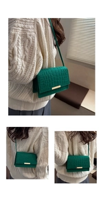 Detailed view of dark green crocodile pattern crossbody bag with gold buckle on model