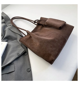 Detail of vintage brown tote bag with matching coin purse on a minimalist gray blazer background