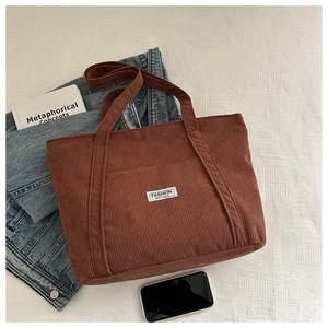 Detail view of brown corduroy tote bag with Fashion Instinct label and vertical texture