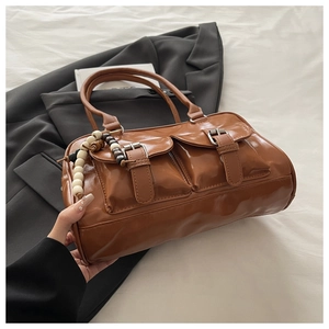 Detail of vintage brown glossy leather tote bag featuring dual front pockets and bead charm