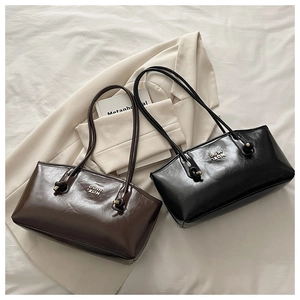 Close-up of knotted handles and gold metal hardware on shiny leather tote bags