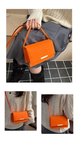 Detail of orange crocodile pattern crossbody bag with gold buckle and adjustable strap