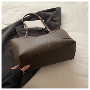 Macro shot of dark brown pebbled leather texture and reinforced stitching on tote bag