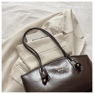 Detail of dark brown tote bag with gold COIH 2DN logo and stylish knotted shoulder strap