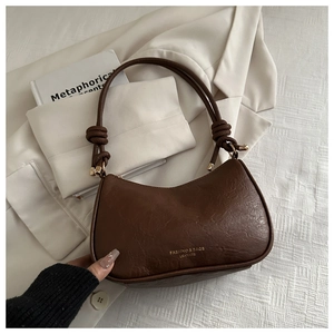 Detail of vintage brown leather handbag texture with decorative knot and gold hardware