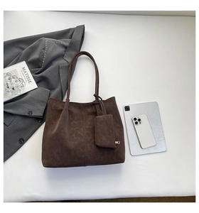 Flat lay of brown suede tote bag with matching mini pouch and office accessories