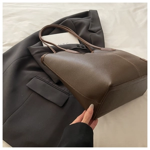 Detail of dark brown pebble leather tote bag with sturdy base and fine stitching
