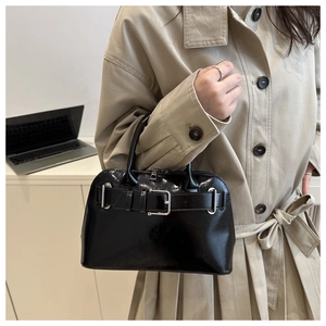 Detail of high-gloss black handbag with silver buckle and sleek patent finish