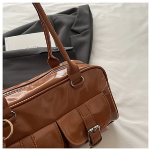 Detail view of retro caramel brown PU leather handbag with front buckle pockets and long strap