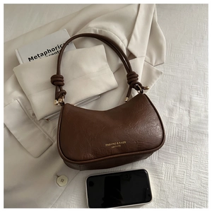 Detail of dark brown crescent underarm bag with litchi grain texture and metal buckle