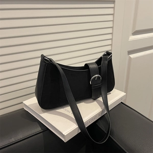 Sac à bandoulière noir minimaliste avec boucle argentée sur support de livre