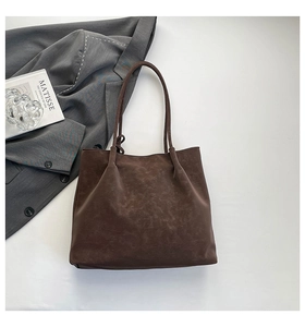 Macro detail of large brown tote bag showing retro matte texture and slim shoulder straps