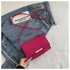 Detail of a mini rose red faux crocodile leather bag with a gold metal buckle