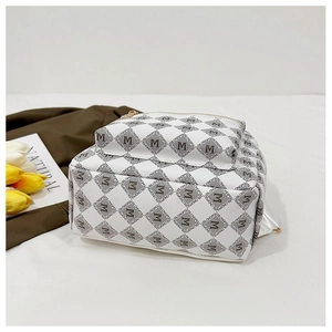 Détail d'un sac à dos matelassé blanc avec imprimé lettres M et zip doré brillant