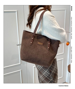Detail of dark brown suede tote bag with leather straps and gold rivet accents