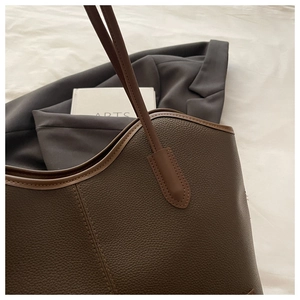Close-up of deep brown tote bag featuring pebbled leather texture and neat stitching