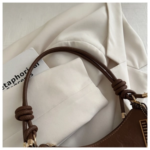 Detail of vintage brown leather crescent bag with knot strap and gold hardware