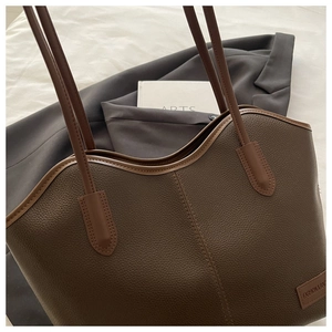 Close-up of brown litchi pattern leather tote bag with fashion label and shoulder strap