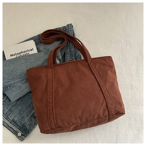 Close-up of brown corduroy tote bag with vertical stripes on a denim jacket backdrop