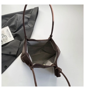 Detail view of large dark brown tote bag with matte texture and magnetic clasp closure