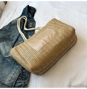Close-up of woven straw tote bag with leather patch and thick white cotton rope handles