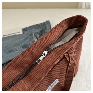 Close-up of brown corduroy tote bag featuring metal zipper and Fashion Instinct label