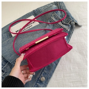 Close-up of magenta felt crossbody bag with gold metal lock on blue denim background