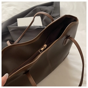 Detail view of large brown lychee grain leather tote bag with sturdy metal zipper closure