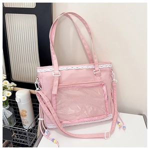 Close-up of pink nylon tote bag featuring delicate white lace trim and transparent mesh pocket