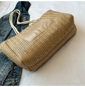 Detail of woven straw tote bag with PU patch and thick cotton rope handles on denim
