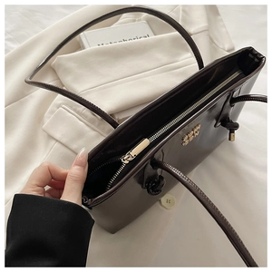 Close-up of deep brown leather shoulder bag with golden zipper and metal logo details