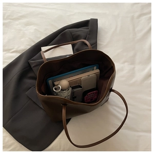 Detailed interior of brown leather tote bag showing large capacity for laptop and books