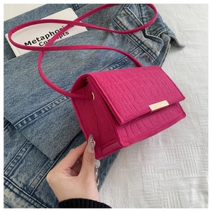 Close-up of fuchsia crocodile pattern crossbody bag with premium gold buckle detail