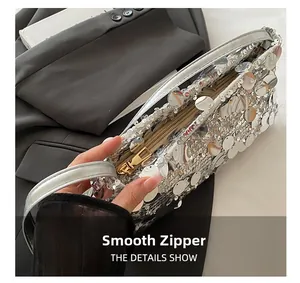 Close-up of smooth gold zipper on a silver sequin evening bag with metallic handle