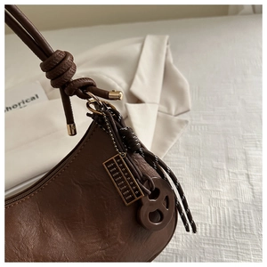 Detail of vintage brown leather underarm bag with abacus charm and knotted strap