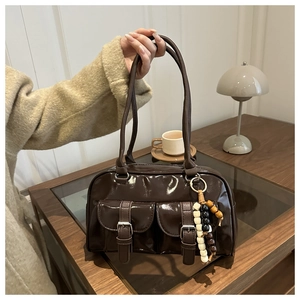Detail of dark brown patent leather handbag with dual front pockets and retro bead charms