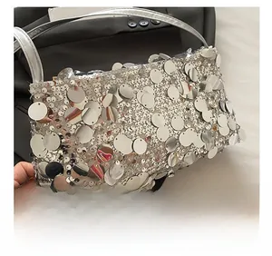 Detailed shot of silver sequin handbag with large metallic discs and slender handle
