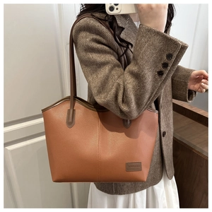 Detailed texture of brown pebble leather tote bag with stylish brand label and shoulder strap