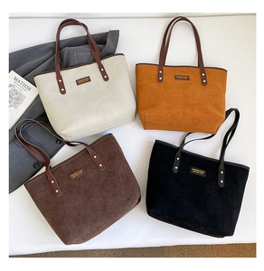 Close-up of four suede tote bags in beige, brown, and black with leather rivet handles