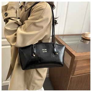 Detail of black glossy shoulder bag with golden logo and vintage knot strap design