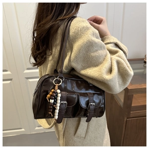 Detail of dark brown patent leather shoulder bag featuring dual front pockets and wood beads